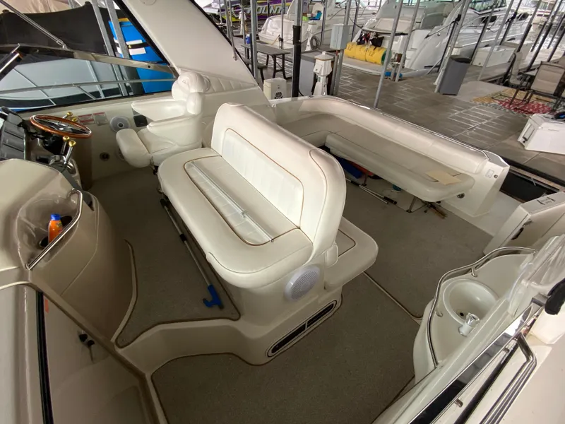 Slide: The Image of 1999 Sea Ray 400 Sundancer interior with white seating and helm, docked in a marina. - 7
