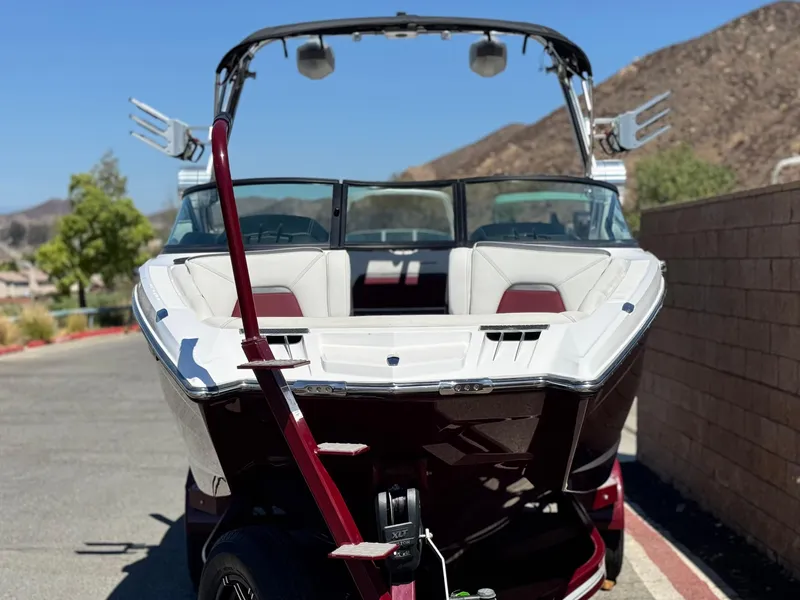 Slide: The Image of 2022 MasterCraft XStar S boat on trailer, parked outdoors with mountainous backdrop. - 2