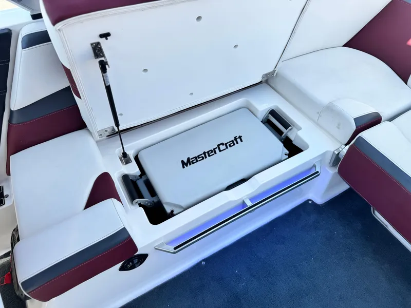 Slide: The Image of 2022 MasterCraft XStar S boat storage compartment with open seat and visible branding. - 25