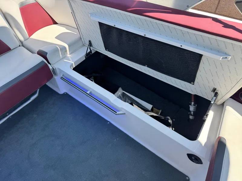 Slide: The Image of Open storage compartment in 2022 MasterCraft XStar S boat with red and white seating. - 28