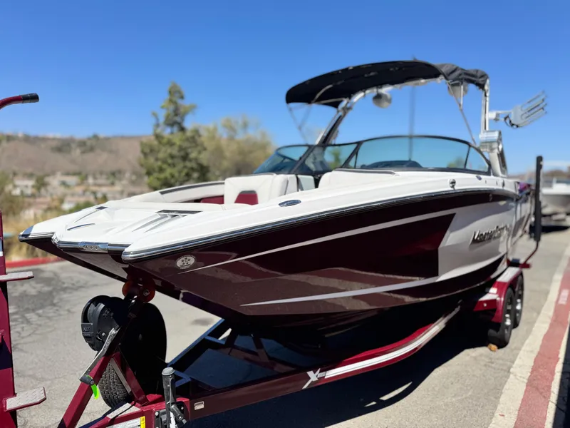Slide: The Image of 2022 MasterCraft XStar S boat on trailer, parked outdoors under clear blue sky. - 3