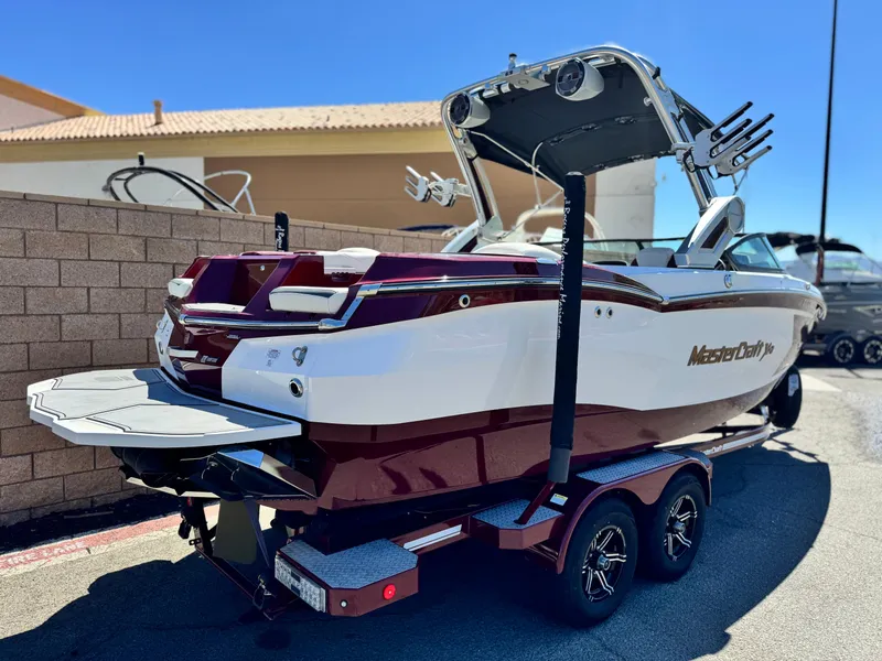 Slide: The Image of 2022 MasterCraft XStar S boat on trailer, parked outdoors under clear blue sky. - 5