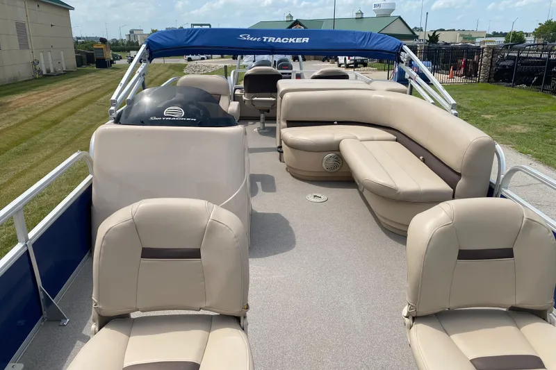 Slide: The Image of 2017 Sun Tracker Fishing Barge 22 with beige seating and blue canopy on a sunny day. - 2