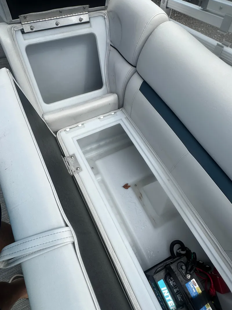Slide: The Image of Open storage compartment in 2022 Godfrey SWEETWATER 2286 SB boat, showing battery and seating. - 19