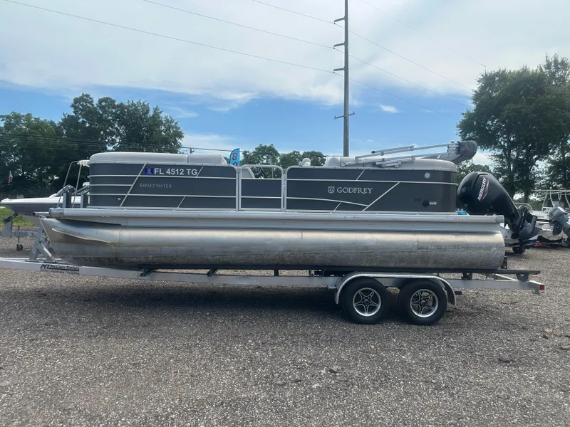 Slide: The Image of 2022 Godfrey SWEETWATER 2286 SB pontoon boat on trailer, parked outdoors. - 2
