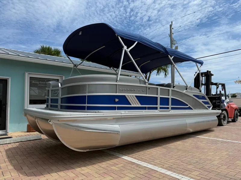 The Image of 2026 Bennington 22 MSB pontoon boat with blue canopy, parked on brick pavement. - 1