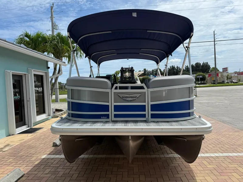 Slide: The Image of 2026 Bennington 22 MSB pontoon boat with blue canopy, parked on brick pavement. - 3