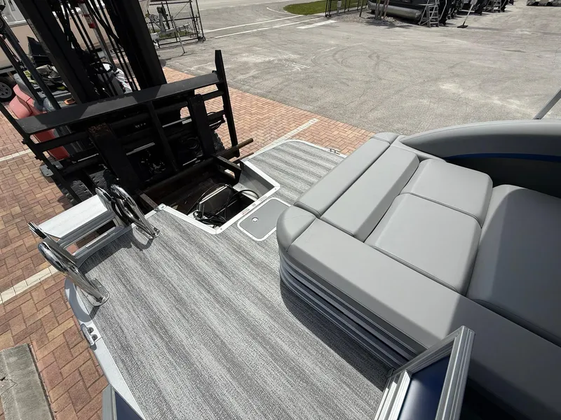 Slide: The Image of 2026 Bennington 22 MSB boat with gray seating and deck, parked near a forklift. - 4