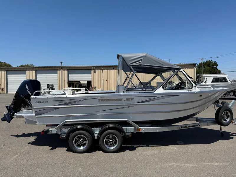 Slide: The Image of 2025 Thunder Jet 210 Luxor boat on trailer, parked outdoors under clear blue sky. - 6