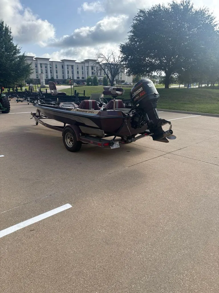Slide: The Image of 1995 Ranger 372V boat with Johnson motor parked outdoors on a sunny day. - 2