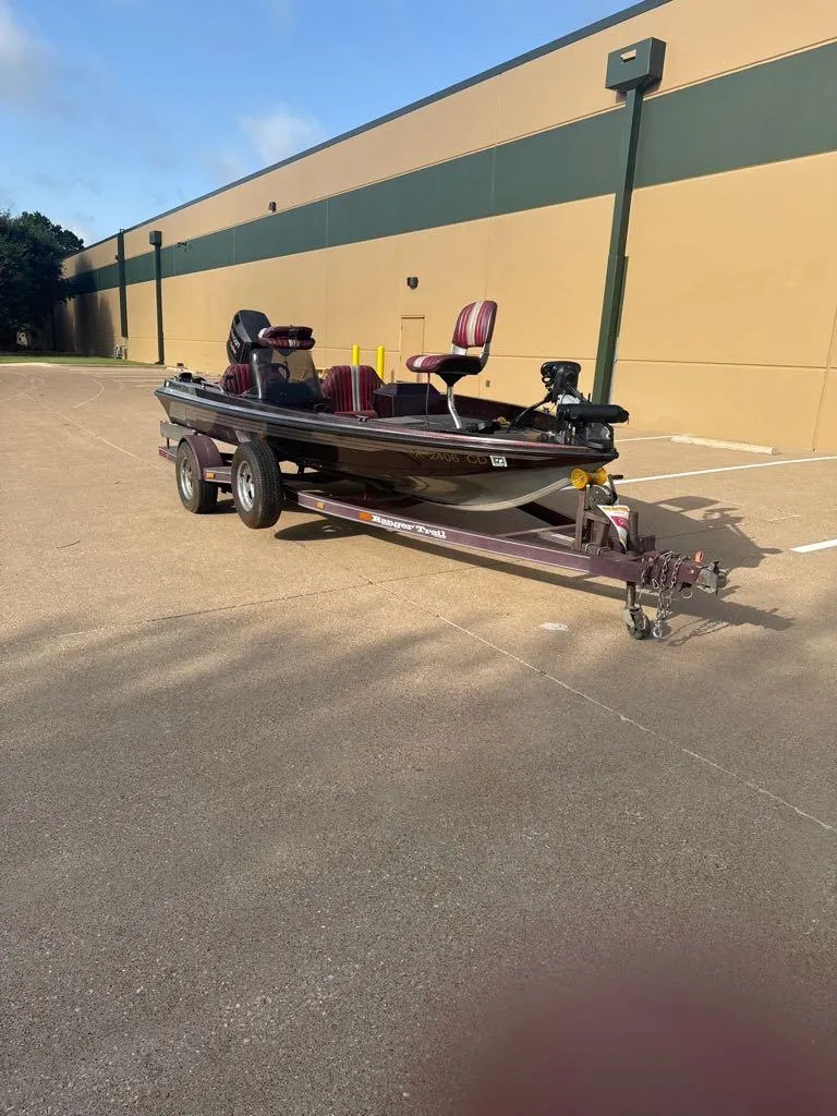 Slide: The Image of 1995 Ranger 372V boat on trailer in parking lot, featuring red seats and dual axles. - 3