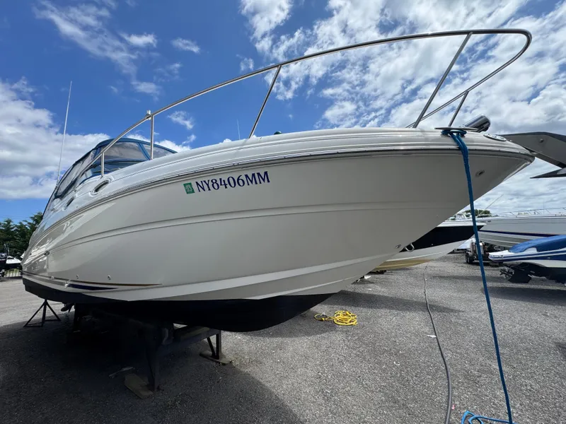 Slide: The Image of 2003 Sea Ray 280 Sundancer boat on dry dock under a blue sky. - 0