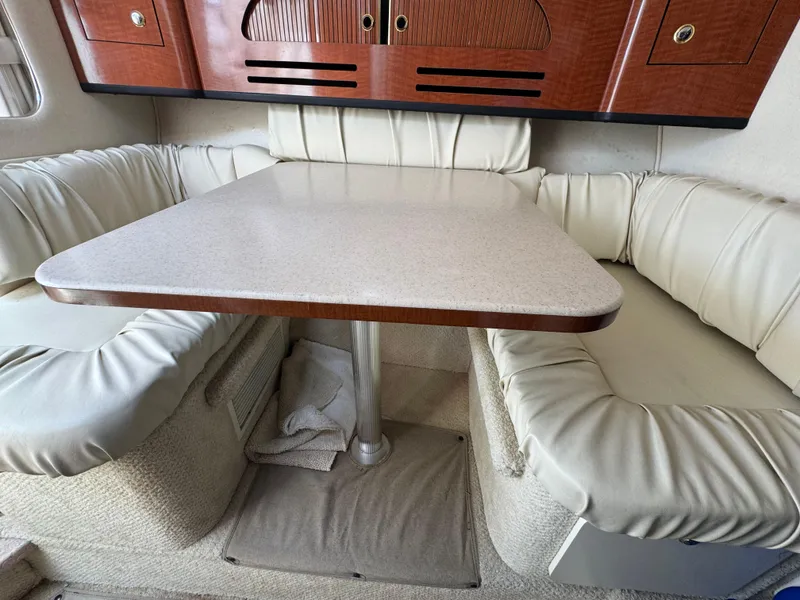 Slide: The Image of 2003 Sea Ray 280 Sundancer cabin with cushioned seating and a central table. - 14