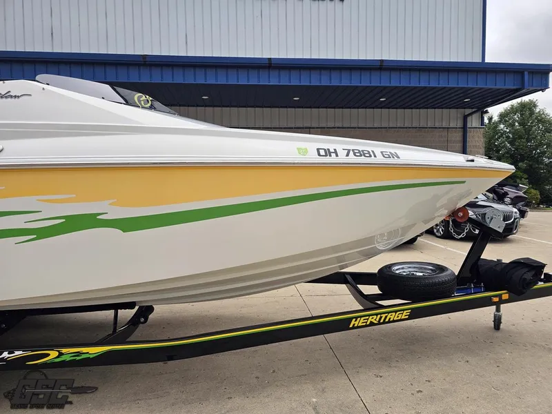 Slide: The Image of 2005 Baja 23 Outlaw boat on trailer with yellow and green graphics. - 13