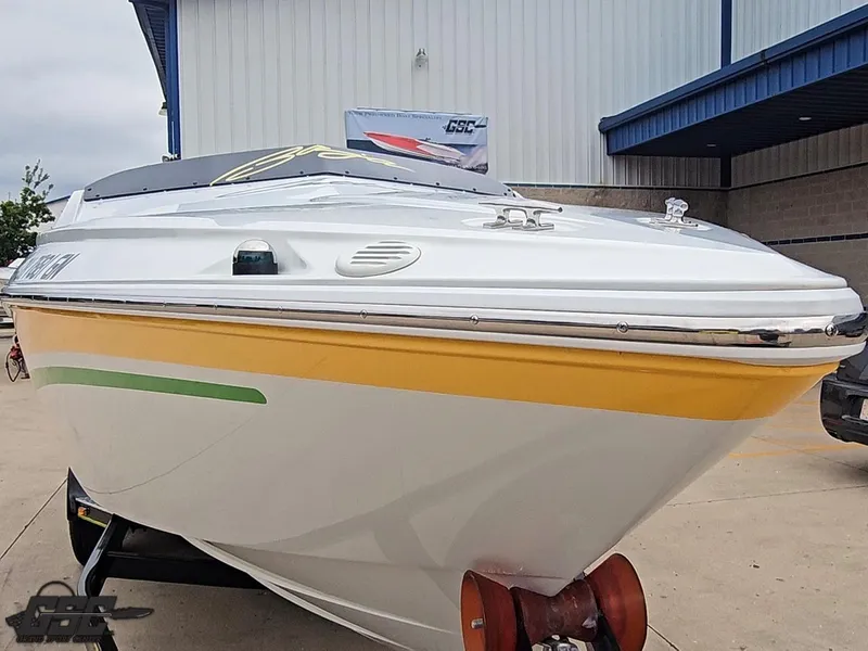 Slide: The Image of 2005 Baja 23 Outlaw boat with yellow and green accents, parked outdoors. - 17