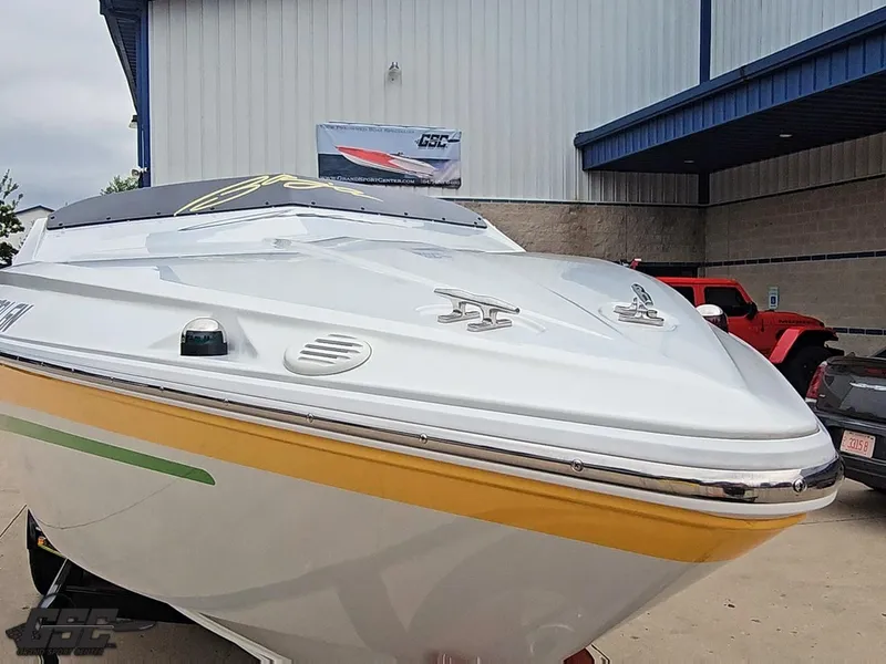 Slide: The Image of 2005 Baja 23 Outlaw boat with sleek design, parked near a building. - 18