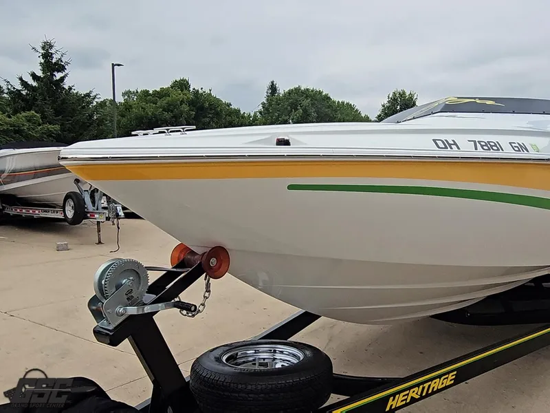 Slide: The Image of 2005 Baja 23 Outlaw boat on trailer, featuring yellow and green accents, parked outdoors. - 21