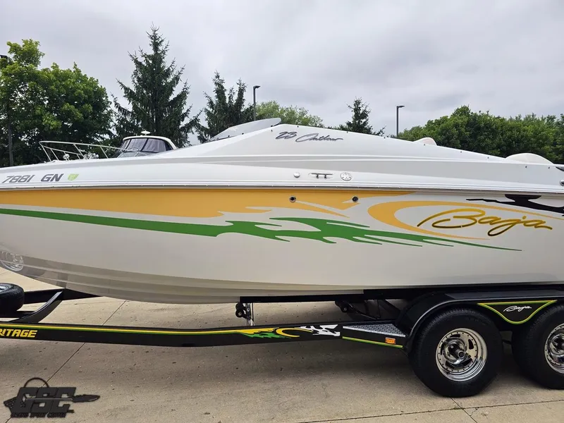 Slide: The Image of 2005 Baja 23 Outlaw boat with vibrant graphics on a trailer, surrounded by trees. - 26