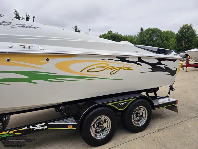 Slide: The Image of 2005 Baja 23 Outlaw boat with vibrant graphics on a trailer, parked outdoors. - 27
