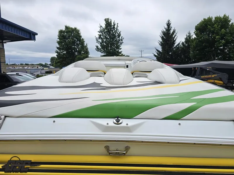 Slide: The Image of 2005 Baja 23 Outlaw boat with vibrant green and yellow design, parked outdoors. - 40