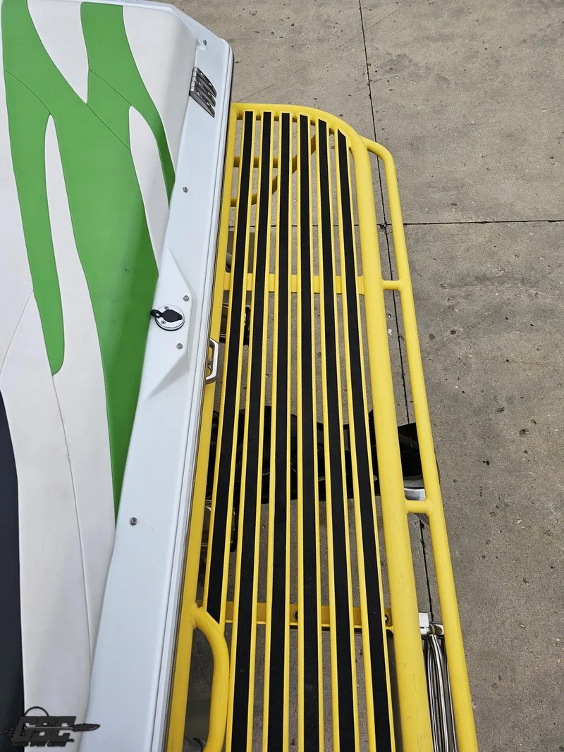 Slide: The Image of 2005 Baja 23 Outlaw boat with green and white design, yellow metal railing. - 42