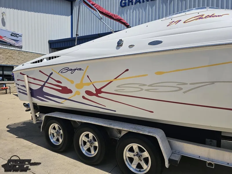 Slide: The Image of 2000 Baja 29 Outlaw boat with colorful graphics on a trailer, parked outdoors. - 10