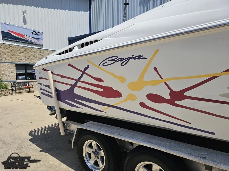 Slide: The Image of 2000 Baja 29 Outlaw boat with colorful graphics on trailer at dealership. - 11