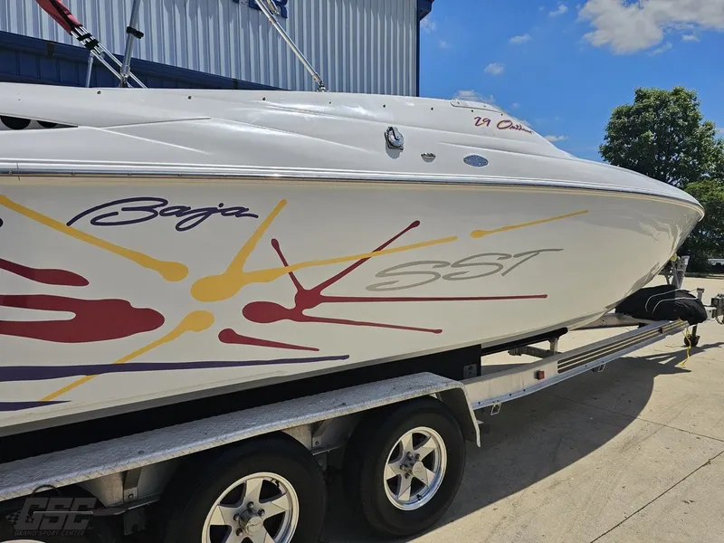 Slide: The Image of 2000 Baja 29 Outlaw boat on trailer, featuring colorful graphics and sleek design. - 13