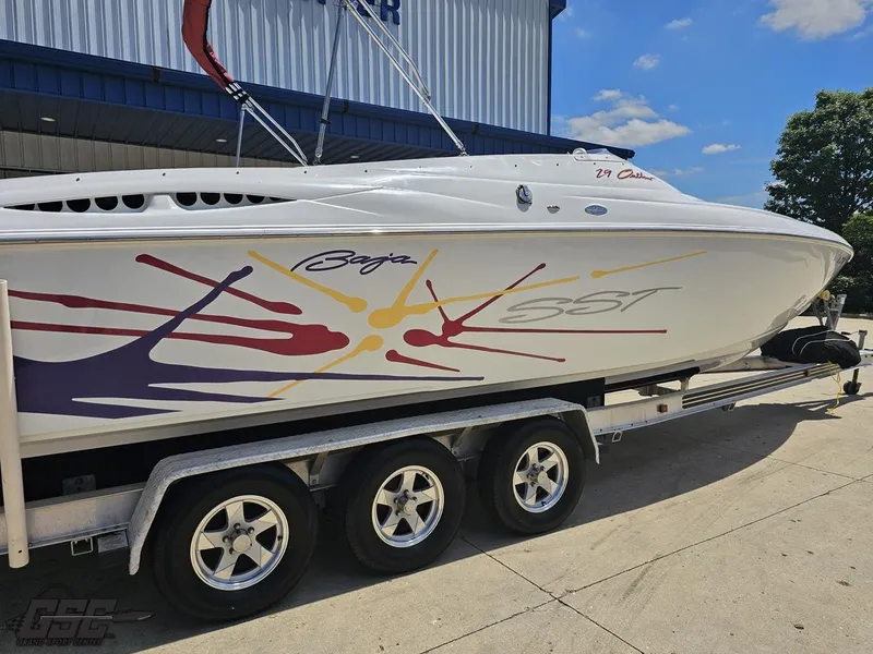 Slide: The Image of 2000 Baja 29 Outlaw boat on trailer, vibrant graphics, parked outdoors. - 14