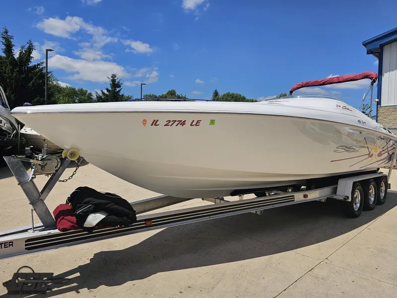 Slide: The Image of 2000 Baja 29 Outlaw boat on trailer under clear blue sky. - 23