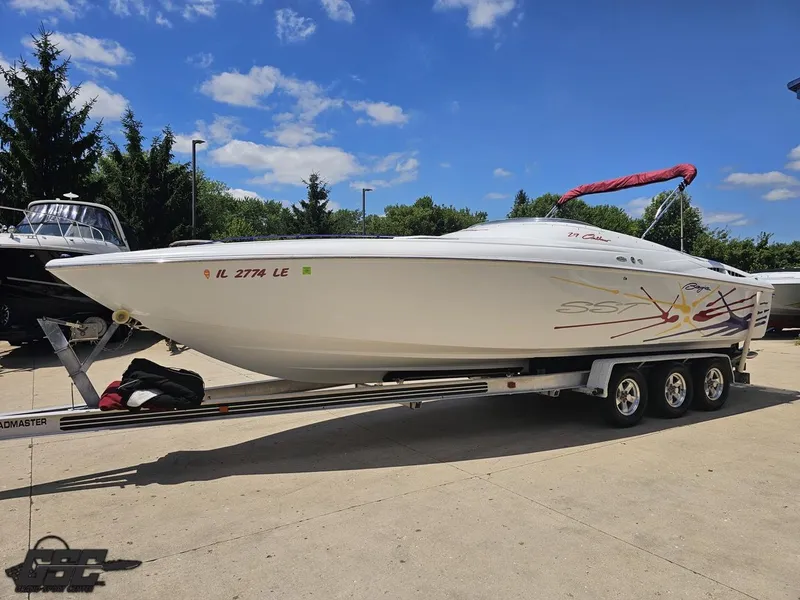 Slide: The Image of 2000 Baja 29 Outlaw boat on trailer, parked outdoors under a clear blue sky. - 24