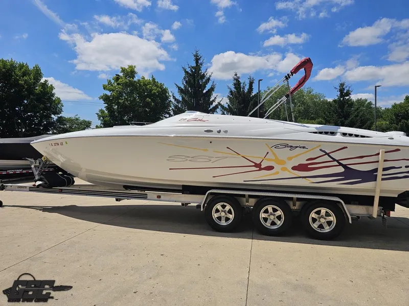 Slide: The Image of 2000 Baja 29 Outlaw boat on trailer, vibrant graphics, clear sky background. - 30