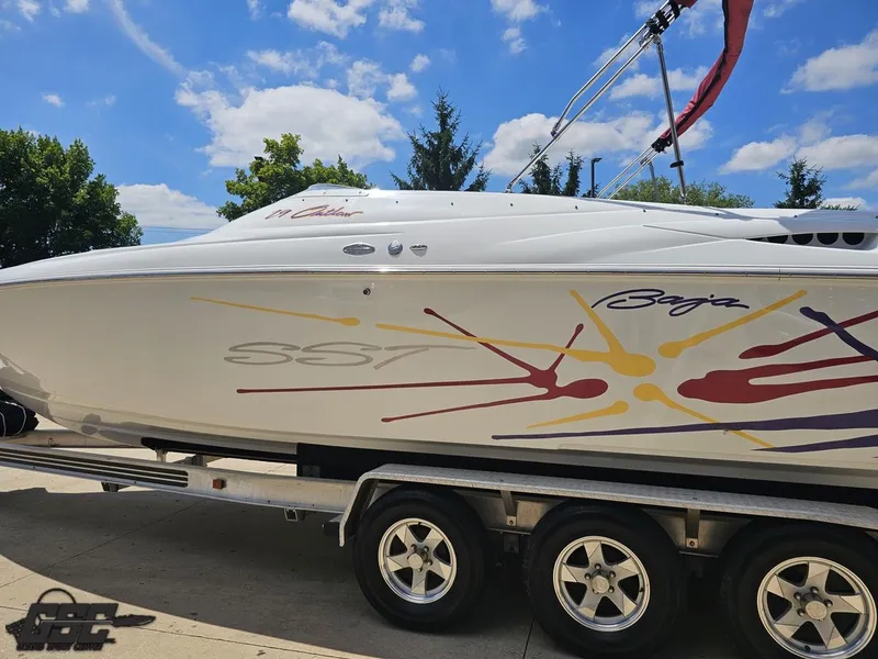 Slide: The Image of 2000 Baja 29 Outlaw boat on trailer under blue sky with colorful graphics. - 31