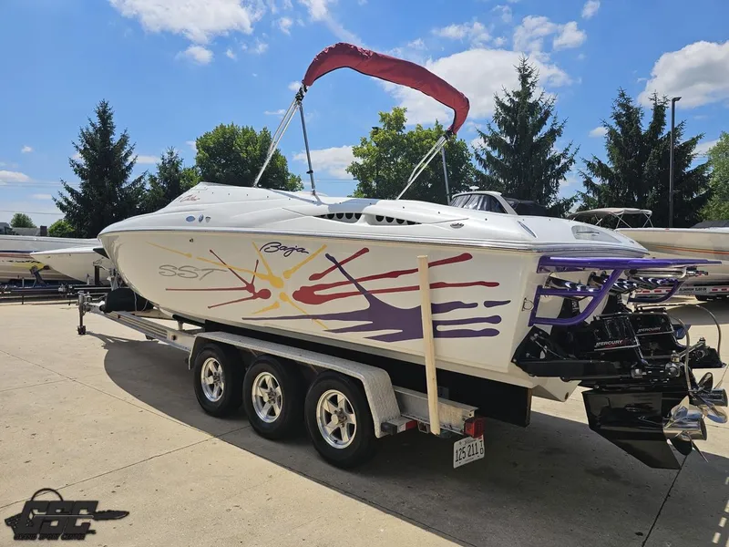 Slide: The Image of 2000 Baja 29 Outlaw boat on trailer, vibrant graphics, sunny day, trees in background. - 39