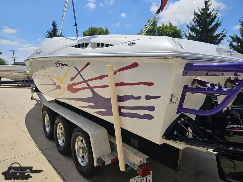 Slide: The Image of 2000 Baja 29 Outlaw boat on trailer, vibrant graphics, sunny day, trees in background. - 40