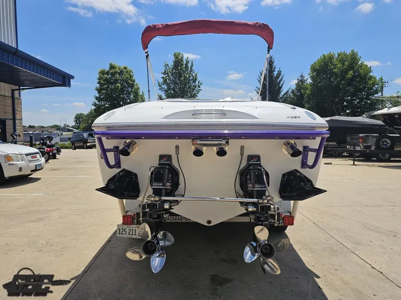 Slide: The Image of 2000 Baja 29 Outlaw boat with dual propellers, parked outdoors under a clear sky. - 44