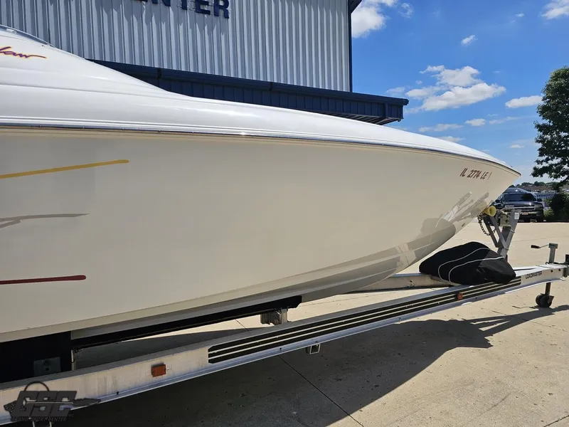 Slide: The Image of 2000 Baja 29 Outlaw boat on trailer, parked outdoors under a clear blue sky. - 9
