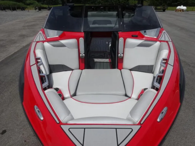 Slide: The Image of 2018 Malibu 23 LSV boat interior with red and white seating, parked outdoors. - 7
