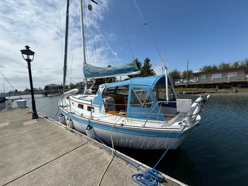 The Image of 1984 Aloha 32 sailboat docked at a marina under a partly cloudy sky. - 1