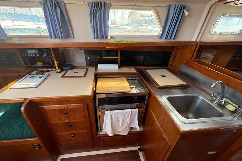 Slide: The Image of 1984 Aloha 32 yacht interior kitchen with stove, sink, and wooden cabinetry. - 12