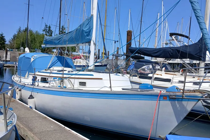 Slide: The Image of 1984 Aloha 32 sailboat docked at marina, featuring blue and white design. - 14
