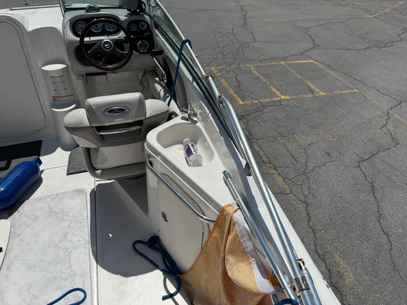 Slide: The Image of 2007 Chaparral 215 SSi boat interior with steering wheel and sink, parked on cracked pavement. - 11