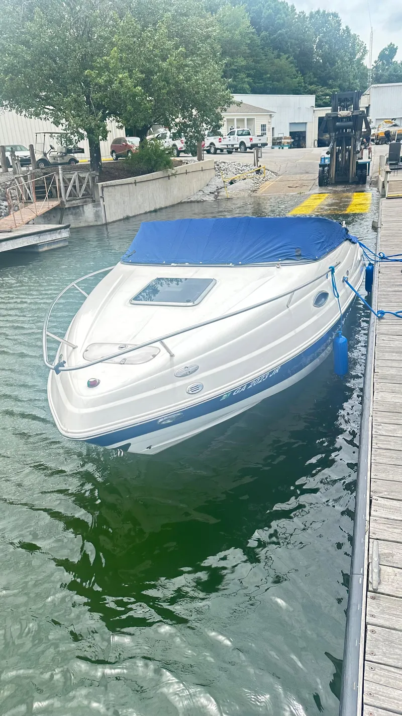 Slide: The Image of 2007 Chaparral 215 SSi boat docked with blue cover, surrounded by water and greenery. - 29