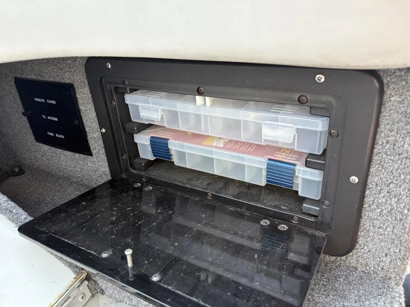 Slide: The Image of Storage compartment in a 2001 Lund 1950 Tyee Magnum GS ITS boat, holding plastic containers. - 16