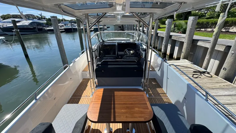 Slide: The Image of Modern Nimbus T9 boat interior with wooden table, cushioned seating, and sleek design, docked at marina. - 18