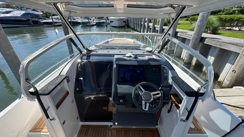 Slide: The Image of 2025 Nimbus T9 boat cockpit with modern steering and controls, docked at a marina. - 41