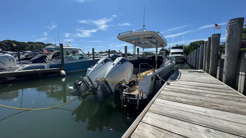 Slide: The Image of Nimbus T9 boat docked at marina, featuring dual outboard motors, under clear blue sky. - 12