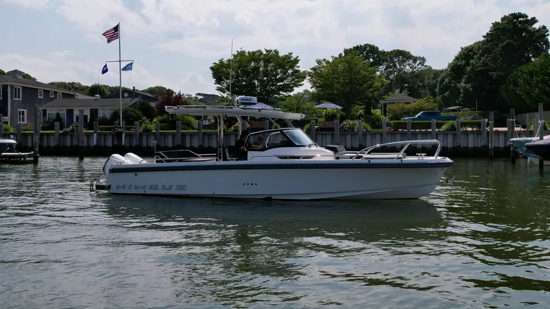 Slide: The Image of Nimbus T9 2025 boat docked in a scenic marina with flags and trees. - 2