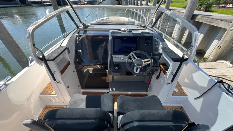 Slide: The Image of Modern Nimbus T9 boat cockpit with dual seats, steering wheel, and navigation display, docked by water. - 23