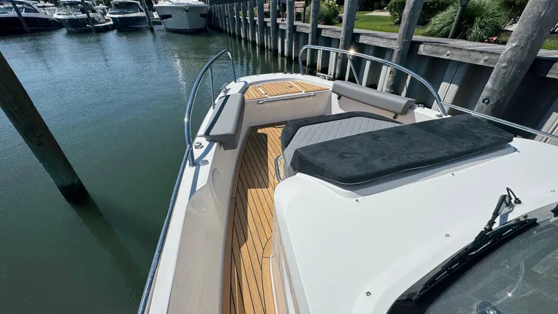 Slide: The Image of 2025 Nimbus T9 boat with teak deck and cushioned seating, docked by wooden pier. - 35